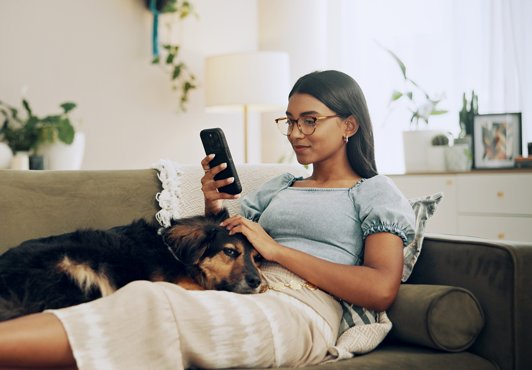 A young woman and her dog relax together while she looks at her phone